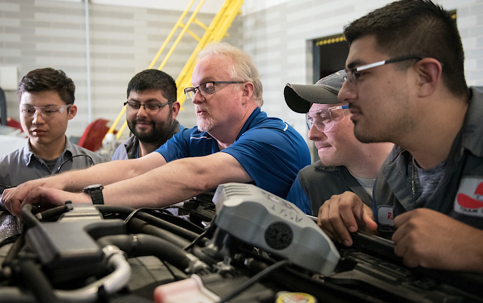 professor and students looking at engine