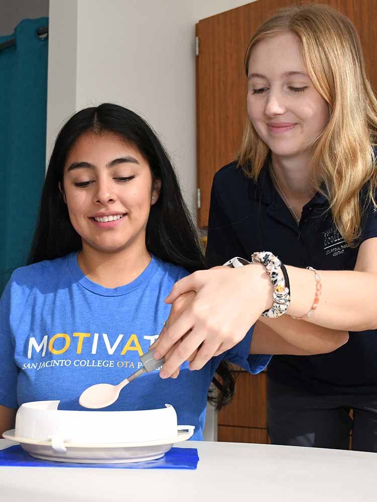 occupational therapy assistant helping patient bring spoon to mouth while trying to eat