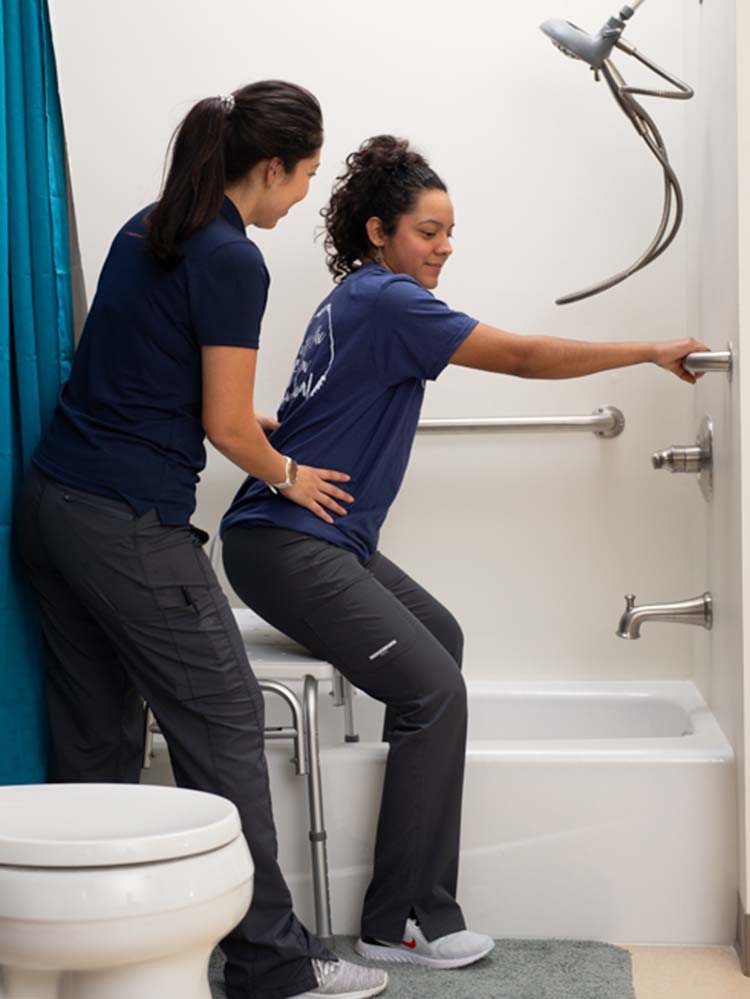 occupational therapy assistant helping patient get into shower