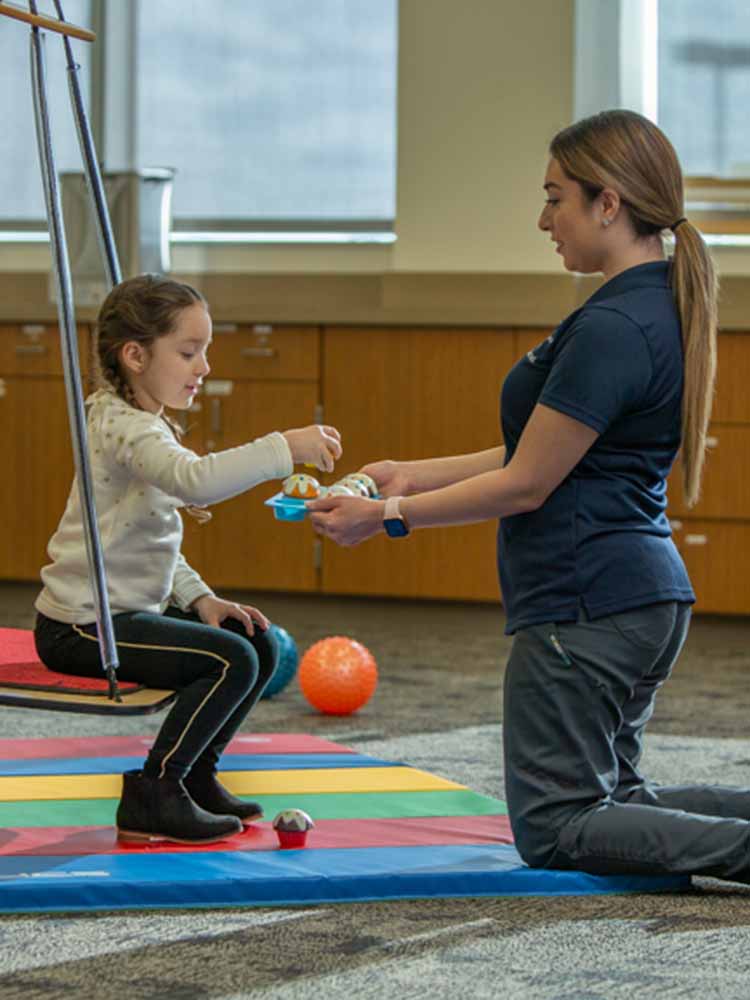 occupational therapy assistant working with child through interactive play